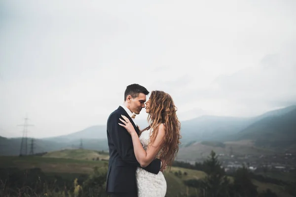 Hermosa pareja de boda besándose y abrazándose cerca de la montaña con vista perfecta —  Fotos de Stock