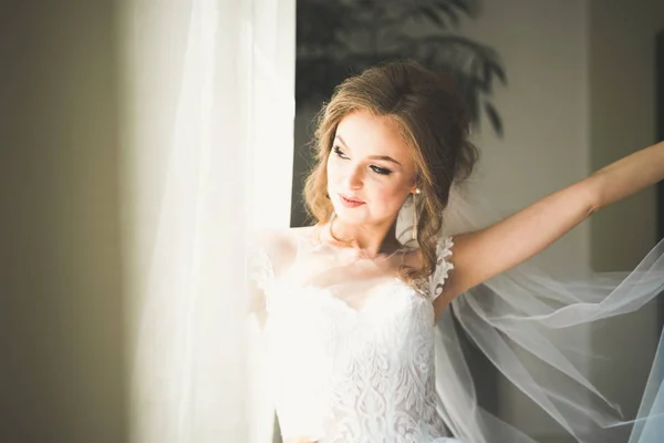 Belle mariée portant une robe de mariée de mode avec des plumes avec luxe délice maquillage et coiffure, studio séance photo d'intérieur — Photo