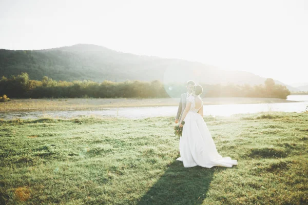 Wunderschöne Braut und stilvoller Bräutigam zu Fuß in sonniger Landschaft, Hochzeitspaar, luxuriöse Zeremonie Berge mit herrlicher Aussicht, Platz für Text — Stockfoto