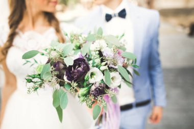 Gelin çiçekli büyük ve güzel bir düğün buketi tutuyor.