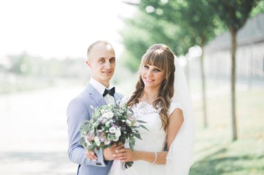 Yeni evli çiftimiz düğün günlerinde ellerinde buketle parkta yürüyorlar.