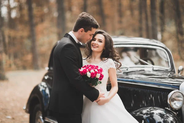 Bella coppia di nozze posa vicino splendida auto retrò — Foto Stock