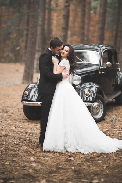 Hermosa pareja de boda posando cerca de espléndido coche retro — Foto de Stock