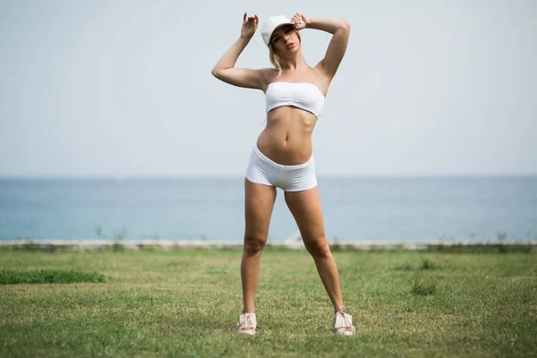 Menina fitness com um corpo perfeito está sorrindo perto do mar — Fotografia de Stock