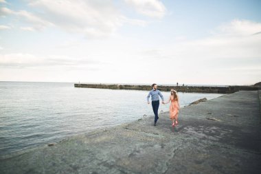 Güzel sevgi dolu çift, gurur iskelede yürüyüş uzun elbise ile