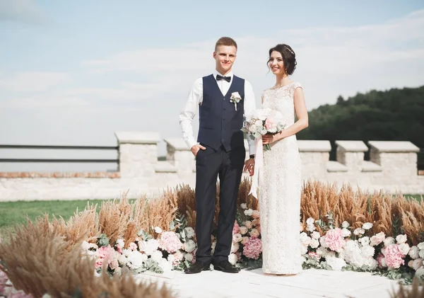 Romantický, pohádkový, šťastný novomanželský pár objímající a líbající se v parku, stromy v pozadí — Stock fotografie