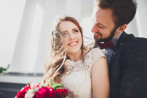 Beautiful couple, bride and groom posing near big white column — Stock Photo, Image