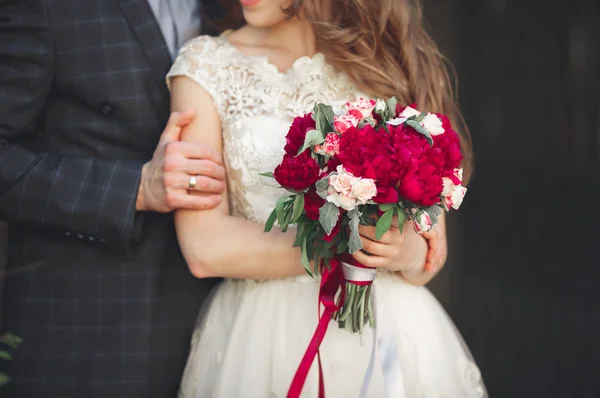 Kucaklayan Düğün çifti, sarılma onun elinde bir buket çiçek tutan gelin damat — Stok fotoğraf