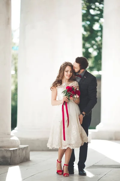 Красивая пара, невеста и жених позируют возле большой белой колонны — стоковое фото