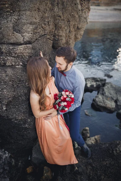 Matrimonio coppia baci e abbracci su rocce vicino al mare blu — Foto Stock