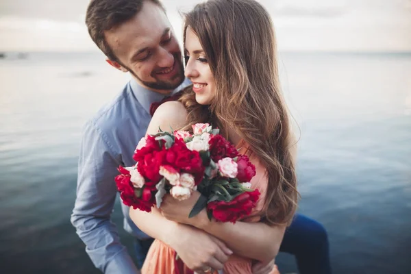 Hochzeitspaar küsst und umarmt sich auf Felsen nahe blauem Meer — Stockfoto