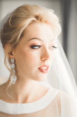 Beyaz elbiseli lüks gelin düğün törenine hazırlanırken poz veriyor.