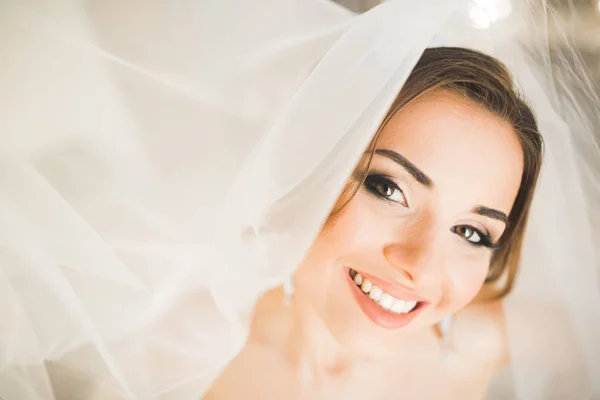 Preciosa novia en bata posando y preparándose para la ceremonia de boda cara en una habitación —  Fotos de Stock