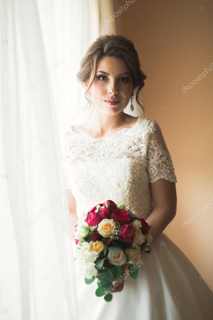 Luxury bride in white dress posing while preparing for the wedding ceremony