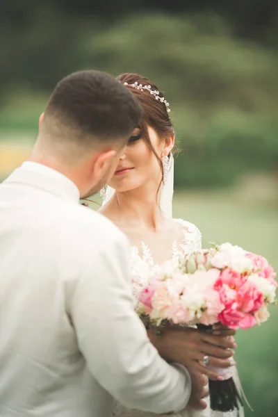 Casal elegante de recém-casados felizes andando no parque em seu dia de casamento com buquê — Fotografia de Stock