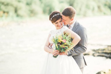 Zarif nazik şık damat ve gelin taşlarla Nehri yakınında. Evlilik çift aşık