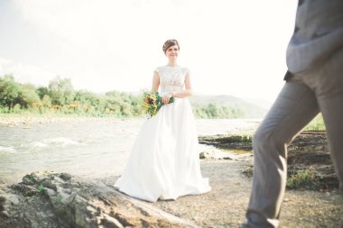 Zarif nazik şık damat ve gelin taşlarla Nehri yakınında. Evlilik çift aşık