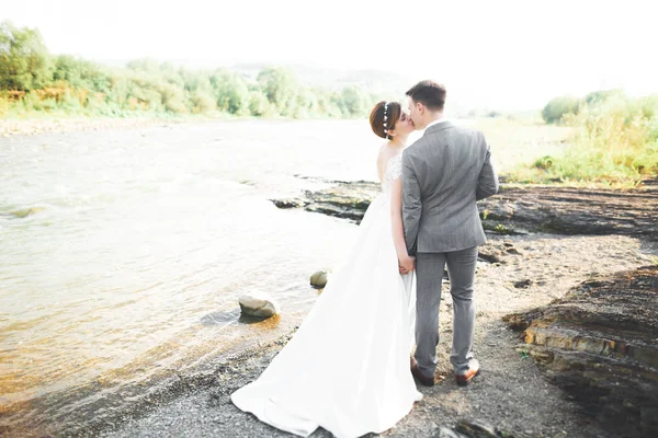 Novia y novio celebrando hermoso ramo de bodas. Posando cerca del río —  Fotos de Stock