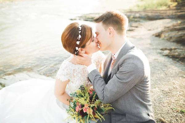 Élégant marié élégant doux et la mariée près de la rivière avec des pierres. Couple de mariage amoureux — Photo