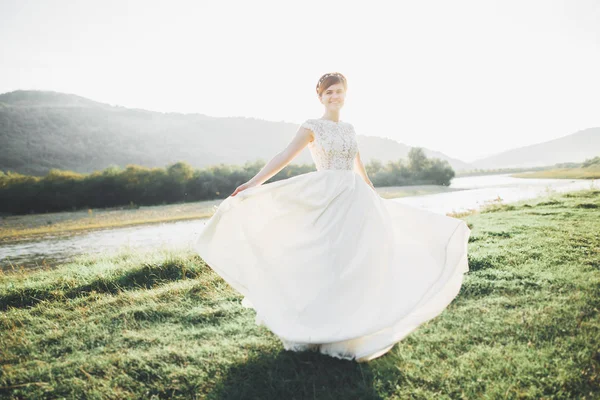 Sposa in abito da sposa in posa su erba con bel paesaggio sfondo — Foto Stock