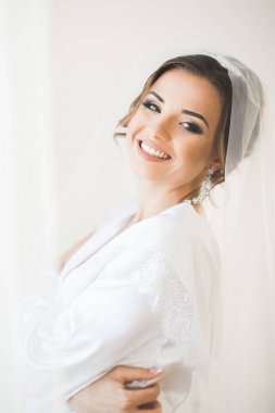 Cüppeli muhteşem gelin bir odada düğün töreni için poz veriyor ve hazırlanıyor.