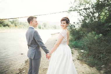 Zarif nazik şık damat ve gelin taşlarla Nehri yakınında. Evlilik çift aşık