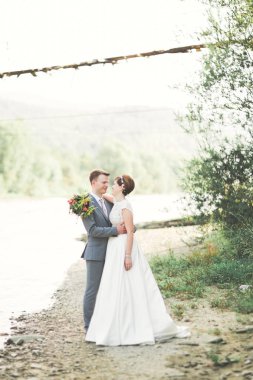 Gelin ve damat güzel düğün buket tutarak. Nehir kenarında poz