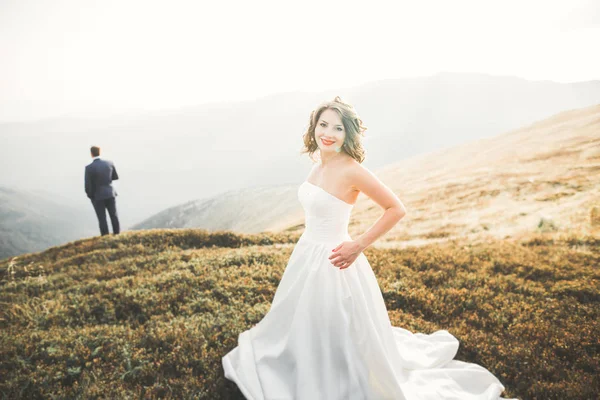 Красива весільна пара позує на вершині гори на заході сонця — стокове фото