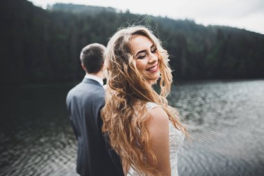 Güzel dağlarda poz veren mutlu bir düğün çifti.