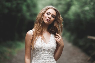 Gelinlik içinde dışarıda poz veren güzel gelin.