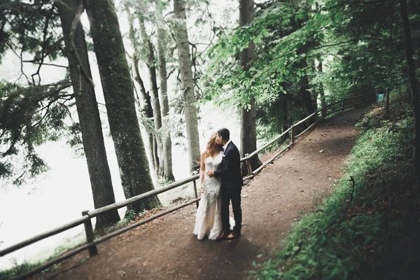 Coppia appena sposata che corre e salta nel parco mentre si tiene per mano — Foto Stock