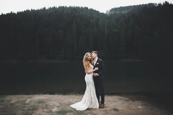 Hermosa pareja de boda besándose y abrazándose cerca de la montaña con vista perfecta —  Fotos de Stock