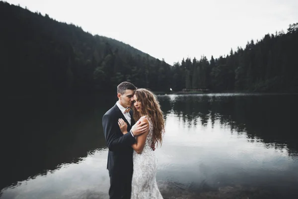 Junges frisch vermähltes Paar, Braut und Bräutigam küssen sich, umarmen sich auf perfektem Blick auf die Berge, blauer Himmel — Stockfoto