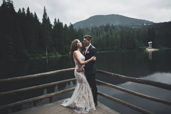 Schönes Hochzeitspaar küsst und umarmt sich in der Nähe des Berges mit perfekter Aussicht — Stockfoto