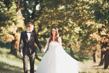 Yeni evli çift el ele tutuşurken parkta koşup zıplıyorlar.