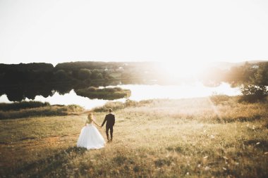 Yeni evli çift el ele tutuşurken parkta koşup zıplıyorlar.