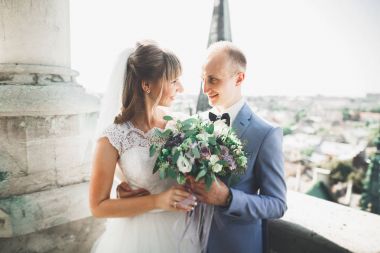 Güzel bir düğün çifti eski kasabanın arka plan panoramik manzarasında öpüşüp sarılıyor.