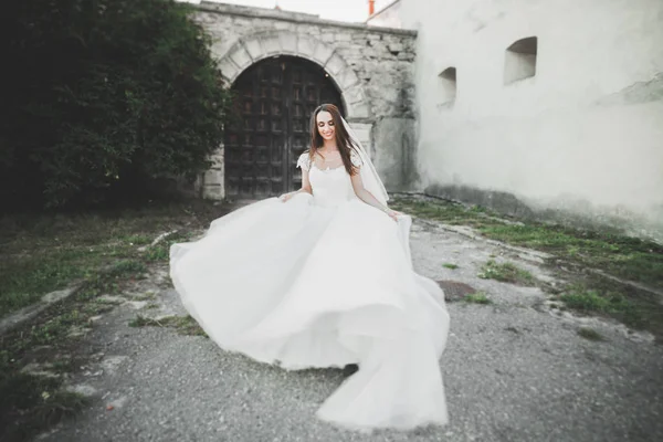 Schöne elegante Braut mit perfektem Brautkleid und Blumenstrauß posiert in der Nähe des alten Schlosses — Stockfoto