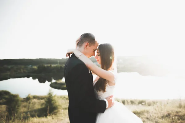 Hermosa pareja romántica de recién casados abrazándose en el parque en la puesta del sol —  Fotos de Stock