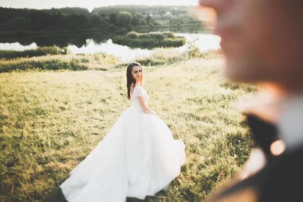 Güzel romantik bir çift yeni evliler gün batımında parkta sarılıyorlar. — Stok fotoğraf