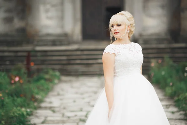 Bella sposa elegante con abito da sposa perfetto e bouquet in posa vicino al vecchio castello — Foto Stock