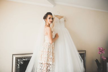 Cüppeli muhteşem gelin bir odada düğün töreni için poz veriyor ve hazırlanıyor.