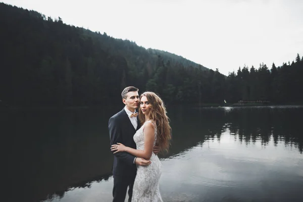 Schönes Hochzeitspaar küsst und umarmt sich in der Nähe des Berges mit perfekter Aussicht — Stockfoto