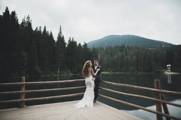 Schönes Hochzeitspaar küsst und umarmt sich in der Nähe des Berges mit perfekter Aussicht — Stockfoto