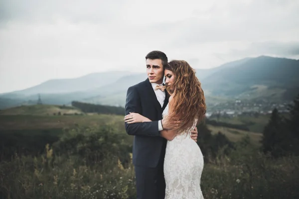 Jeune couple nouvellement marié, embrasser mariée et marié, embrasser sur une vue parfaite sur les montagnes, ciel bleu — Photo