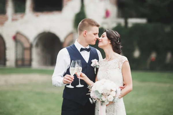 Stilvolles Brautpaar spaziert am Hochzeitstag mit Blumenstrauß durch den Park — Stockfoto