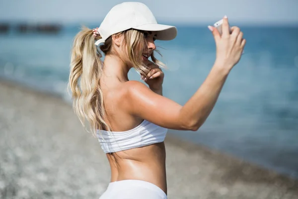 Selfie fitness donna autoritratto dopo l'allenamento. L'atleta sportivo sta scattando foto di selfie dopo aver allenato la corsa e l'allenamento all'aperto sulla spiaggia — Foto Stock