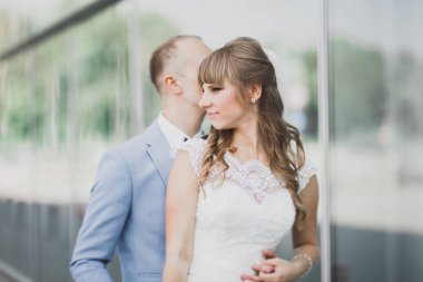 Güzel mutlu düğün çift, uzun beyaz elbise yakındaki modern Binası poz ile gelin