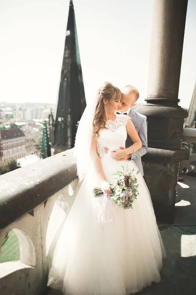 Stílusos szép esküvői pár csók és ölelés a háttérben panorámás kilátás nyílik az óvárosra — Stock Fotó