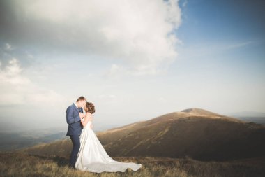 Bir dağın tepesinde günbatımında poz güzel düğün çifti